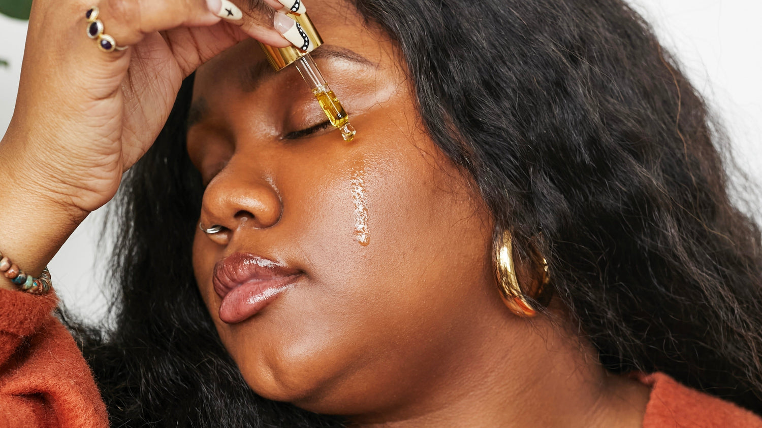 woman applying oil to her cheeks