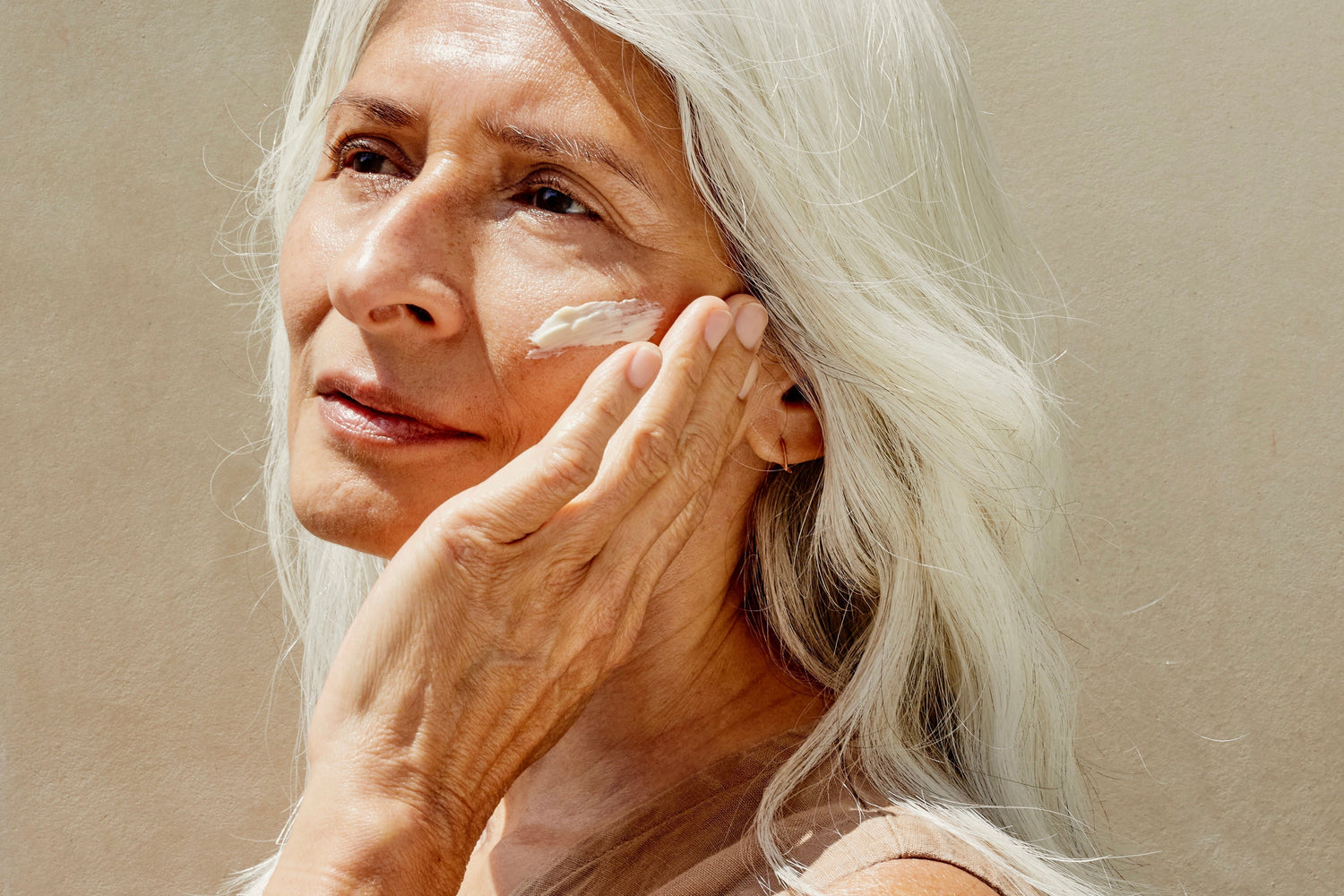 aged woman massaging lotion into her cheeks